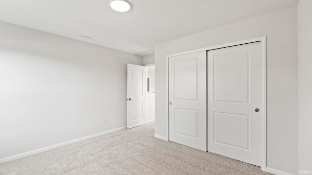 unfurnished bedroom with light carpet and a closet