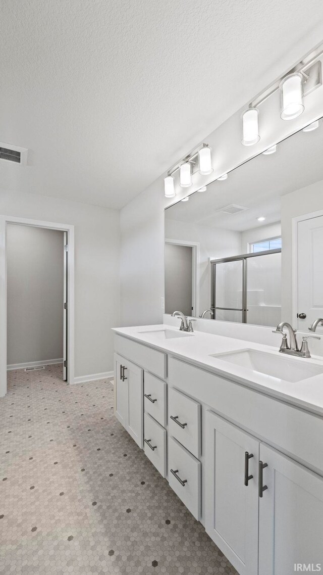 bathroom featuring a textured ceiling, dual vanity, and tile patterned floors