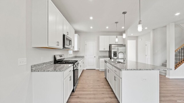 kitchen with sink, light wood-type flooring, an island with sink, and stainless steel appliances