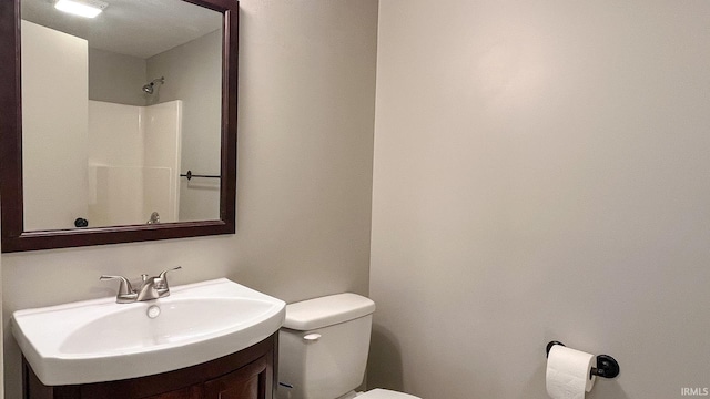 bathroom with vanity, toilet, and a shower