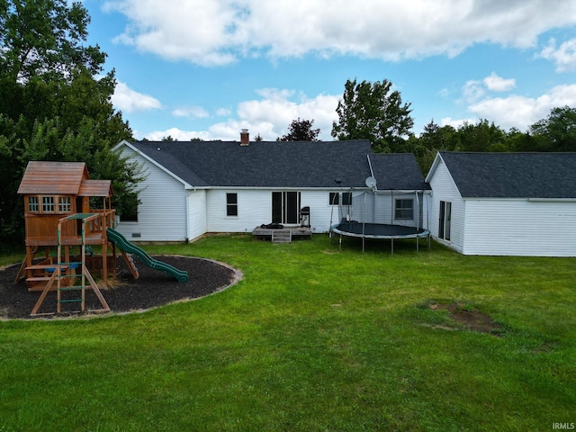 rear view of property featuring a yard, a trampoline, and a playground