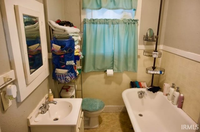 bathroom featuring tile walls, toilet, a bathtub, and vanity