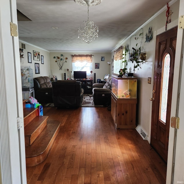 living room with dark hardwood / wood-style floors, crown molding, and an inviting chandelier