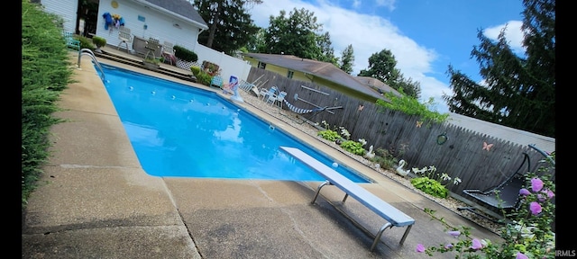 view of swimming pool with a diving board and a patio area