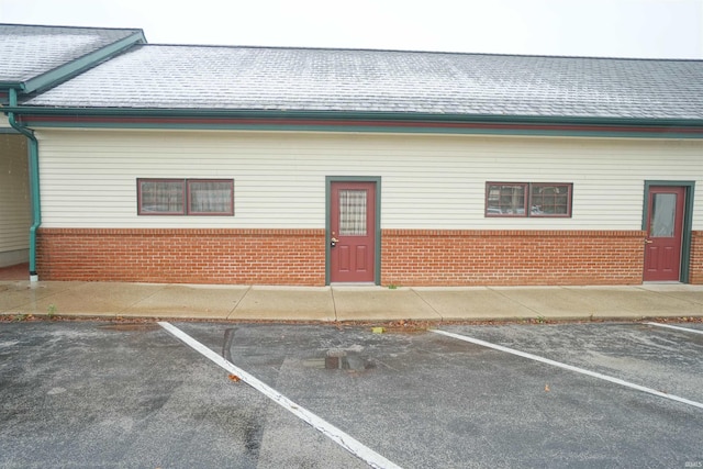 exterior space with uncovered parking, brick siding, and a shingled roof