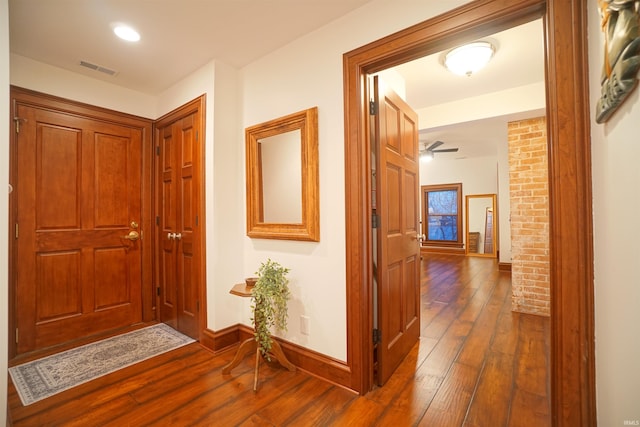 hall featuring visible vents, baseboards, and dark wood finished floors