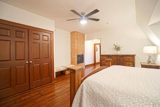 bedroom featuring a closet, a fireplace, a ceiling fan, and dark wood-style flooring