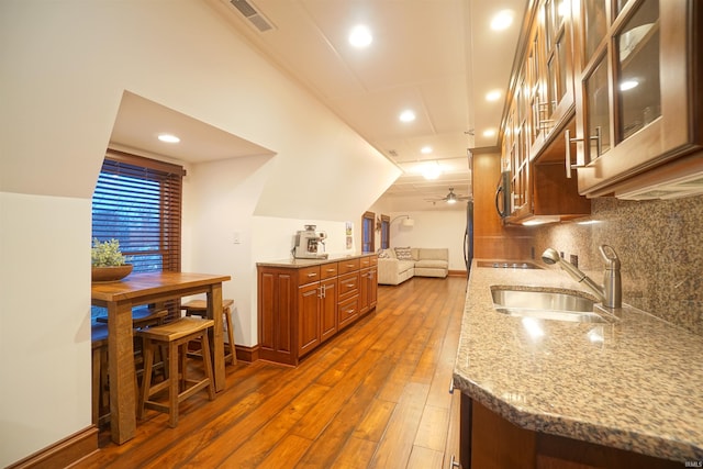 kitchen with light stone counters, a sink, visible vents, tasteful backsplash, and dark wood finished floors