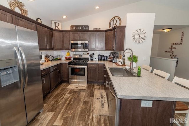 kitchen featuring backsplash, sink, dark wood-type flooring, vaulted ceiling, and stainless steel appliances