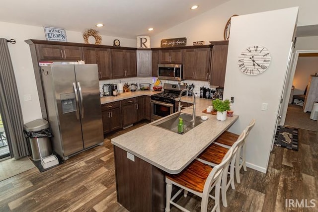 kitchen with decorative backsplash, vaulted ceiling, dark hardwood / wood-style floors, and stainless steel appliances