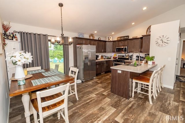 kitchen with vaulted ceiling, an inviting chandelier, dark wood-type flooring, and stainless steel appliances