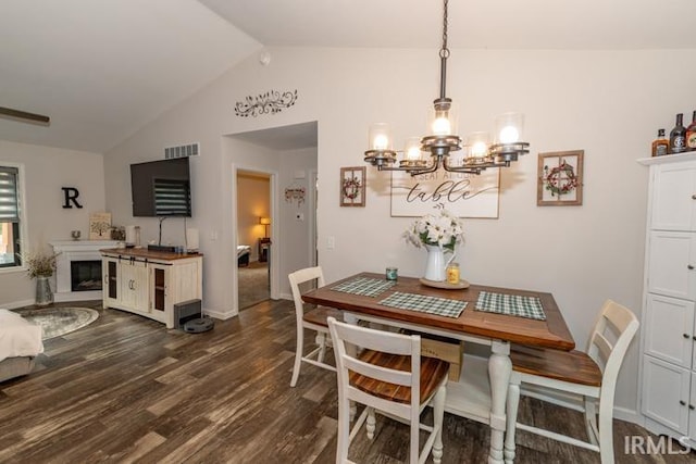 dining space featuring an inviting chandelier, dark hardwood / wood-style flooring, and lofted ceiling