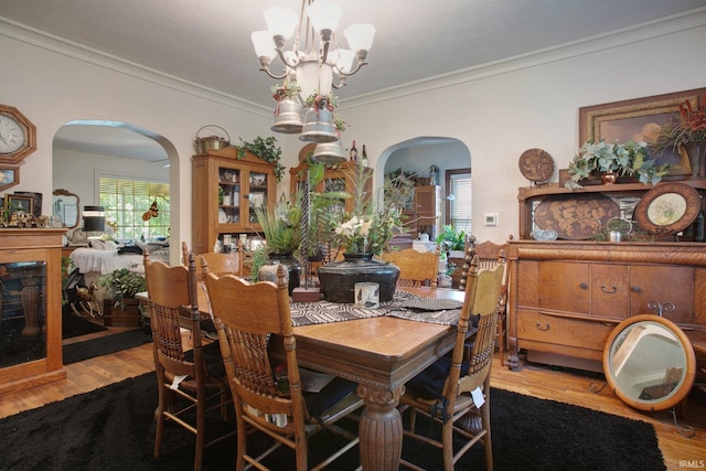 dining area with an inviting chandelier, crown molding, and wood-type flooring