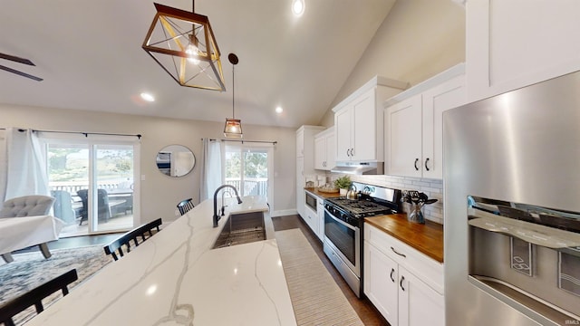 kitchen featuring backsplash, stainless steel appliances, sink, lofted ceiling, and hanging light fixtures