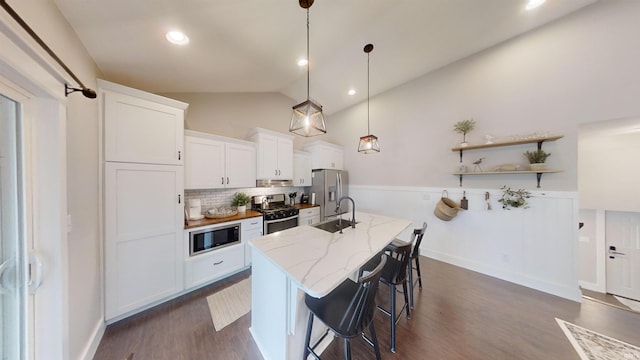 kitchen with sink, dark wood-type flooring, white cabinetry, stainless steel appliances, and pendant lighting