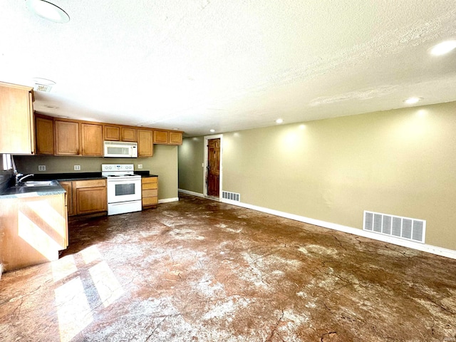 kitchen featuring dark tile patterned flooring, sink, a textured ceiling, and white appliances