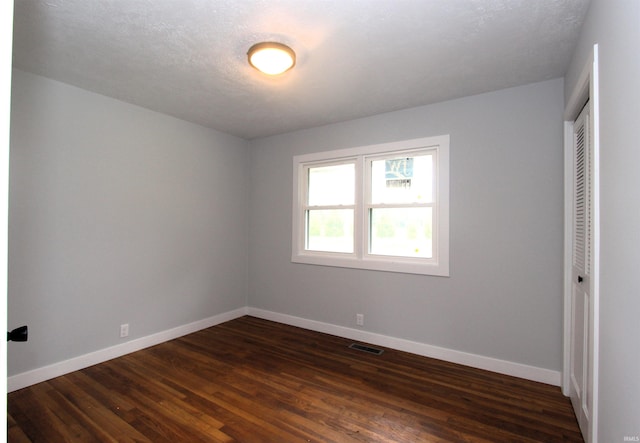 unfurnished bedroom featuring a closet, dark hardwood / wood-style flooring, and a textured ceiling