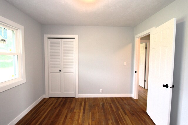 unfurnished bedroom featuring a closet and dark wood-type flooring