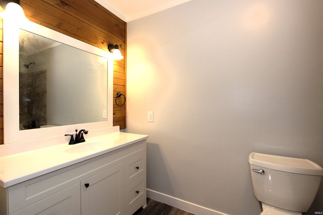 bathroom with wood-type flooring, wood walls, vanity, and toilet