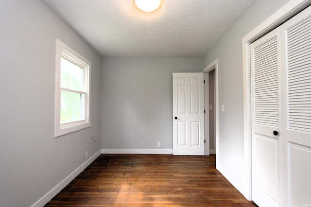 unfurnished bedroom with dark wood-type flooring and a closet