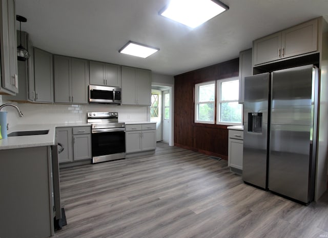 kitchen featuring stainless steel appliances, decorative backsplash, hardwood / wood-style floors, sink, and gray cabinets