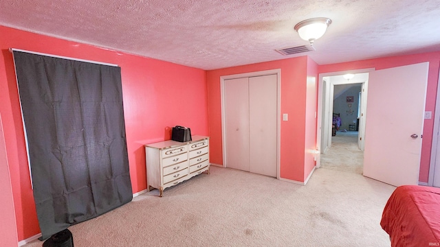 bedroom with light carpet, a textured ceiling, and a closet