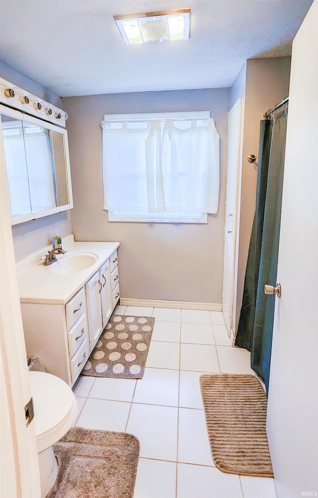 bathroom with toilet, vanity, and tile patterned floors