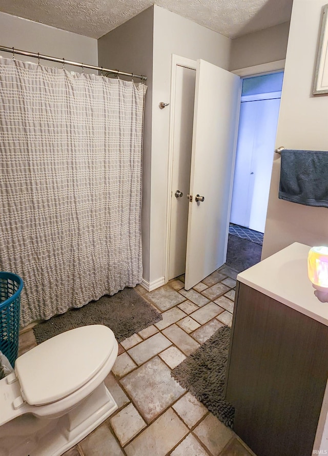 bathroom with tile patterned floors, toilet, a textured ceiling, and vanity