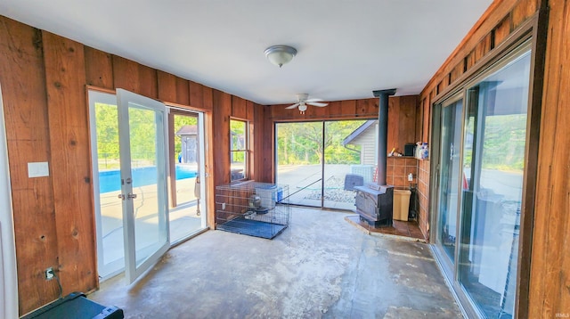 unfurnished sunroom with ceiling fan, french doors, and a wood stove