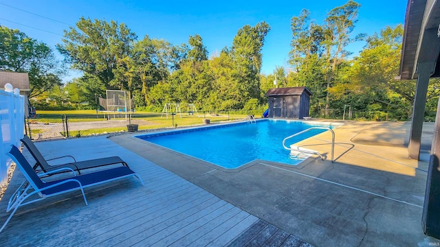 view of swimming pool with a wooden deck, a storage shed, a patio, and a yard