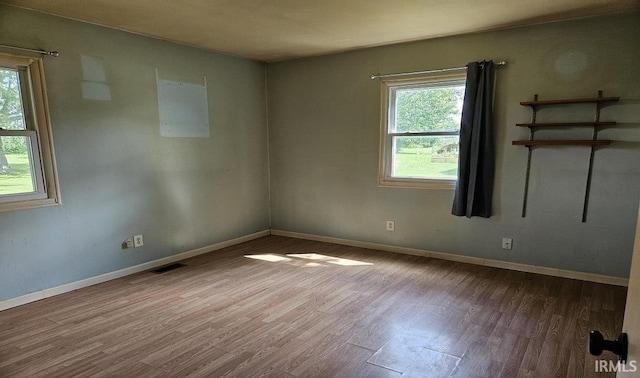 empty room with visible vents, baseboards, and wood finished floors