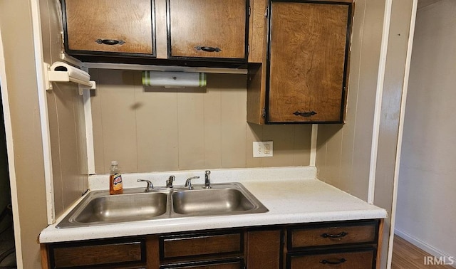 kitchen with light countertops, dark brown cabinets, and a sink