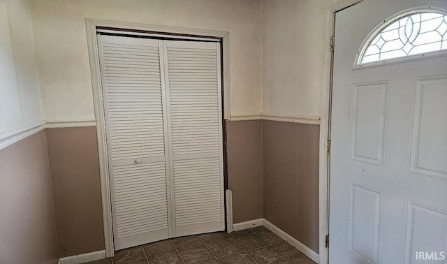 entryway with baseboards and dark tile patterned flooring