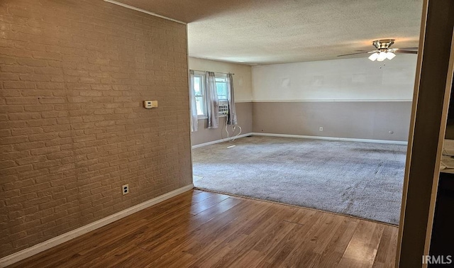 empty room featuring ceiling fan, a textured ceiling, baseboards, and wood finished floors