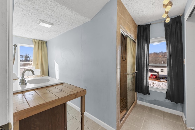 bathroom with a textured ceiling, a stall shower, a wealth of natural light, and tile patterned floors