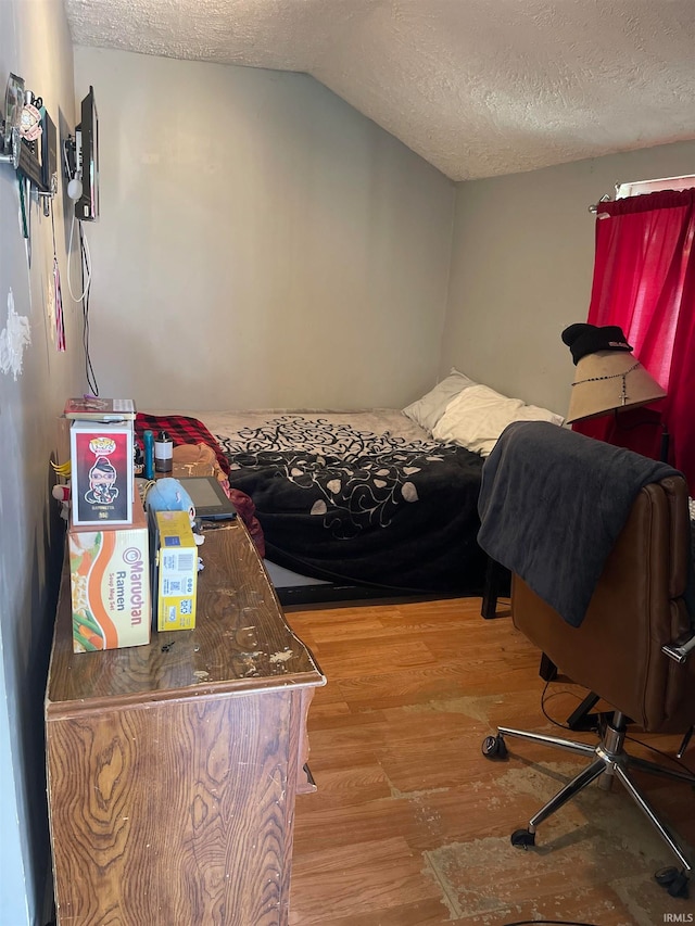 bedroom featuring a textured ceiling, vaulted ceiling, and hardwood / wood-style floors