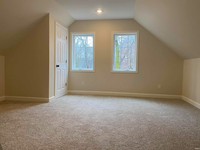 additional living space featuring light colored carpet and vaulted ceiling