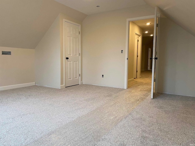 additional living space with light carpet and vaulted ceiling