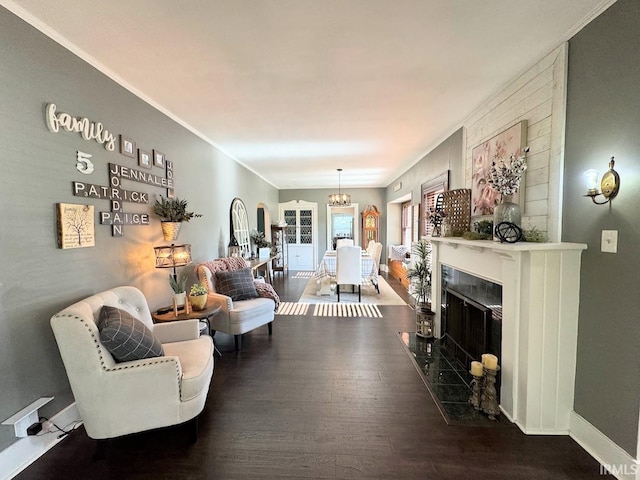 living room with wood-type flooring, a premium fireplace, ornamental molding, and a chandelier