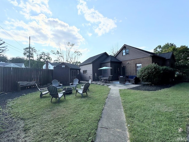 rear view of property featuring a fire pit, fence, a lawn, an outdoor structure, and a patio area