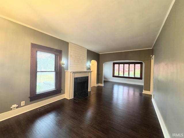 unfurnished living room with visible vents, a fireplace with flush hearth, dark wood-style floors, crown molding, and baseboards