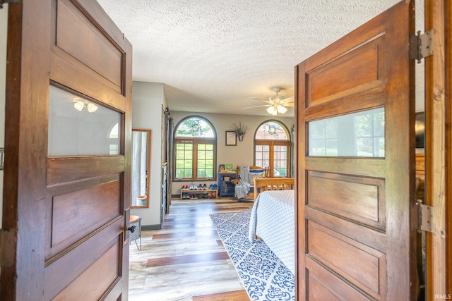 foyer featuring light wood-type flooring, ceiling fan, and a textured ceiling