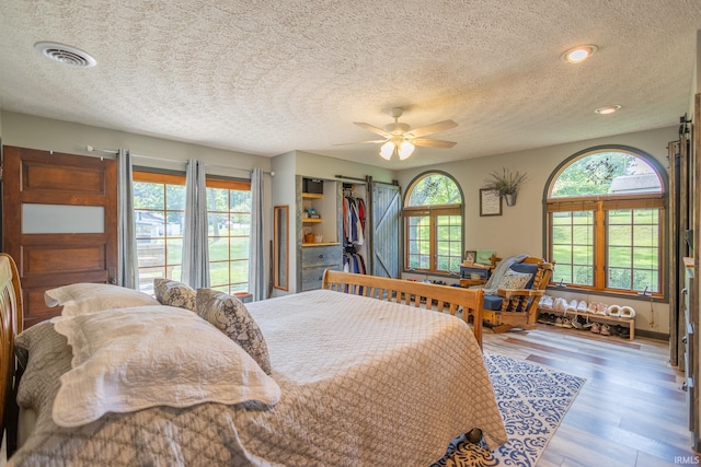 bedroom featuring multiple windows, ceiling fan, a textured ceiling, and wood-type flooring