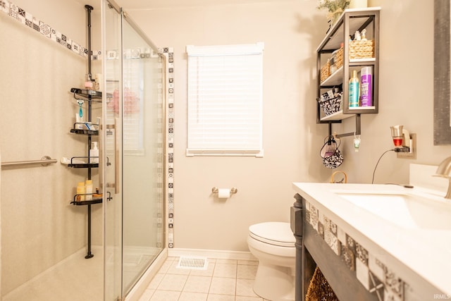 bathroom featuring tile patterned flooring, a shower with door, vanity, and toilet