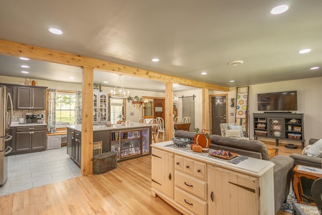 kitchen with stainless steel fridge, backsplash, ornate columns, a center island, and light tile patterned flooring