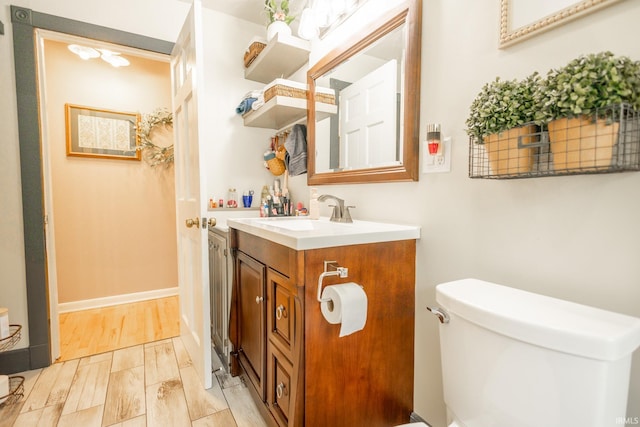 bathroom with wood-type flooring, toilet, and vanity