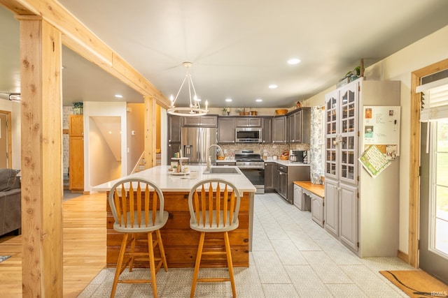 kitchen featuring stainless steel appliances, light hardwood / wood-style flooring, an island with sink, and a healthy amount of sunlight