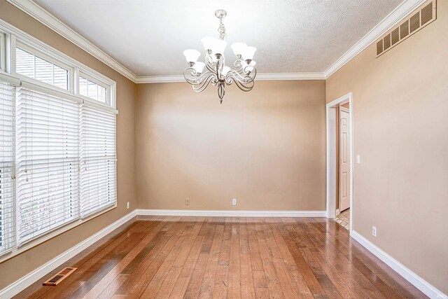 empty room featuring hardwood / wood-style flooring, crown molding, a textured ceiling, and a chandelier