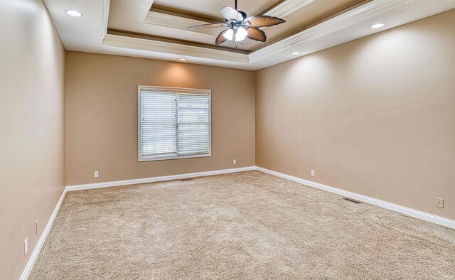 spare room with ceiling fan, carpet floors, and a tray ceiling