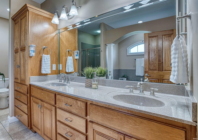 bathroom featuring vanity, a shower with door, toilet, and tile patterned floors